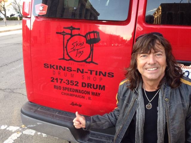 Image: REO Speedwagon drummer Brian Hitt gives a thumbs up behind the red van owned by Skins n' Tins. Photo provided by Skins 'n Tins.