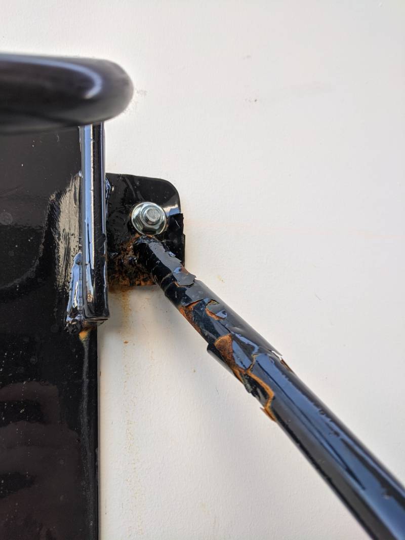 Image: An extreme close up of a portion of the bike hook. It shows a black bar that is beginning to rust. 