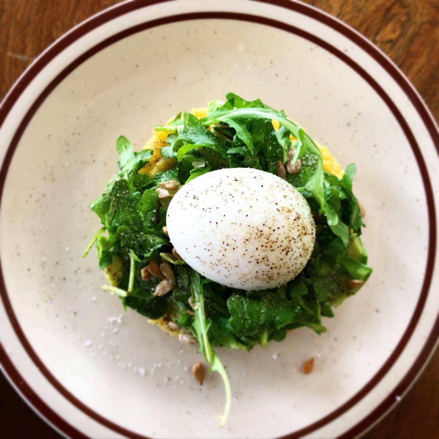Poached egg sits atop a bed of greens, seeds, avocado, and grits. Photo by Alyssa Buckley.