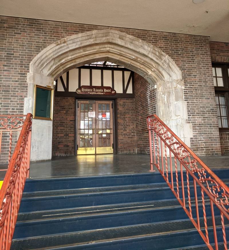 Image: The interior entrance to the Urbana hotel. It is a brick facade with a sign that says 
