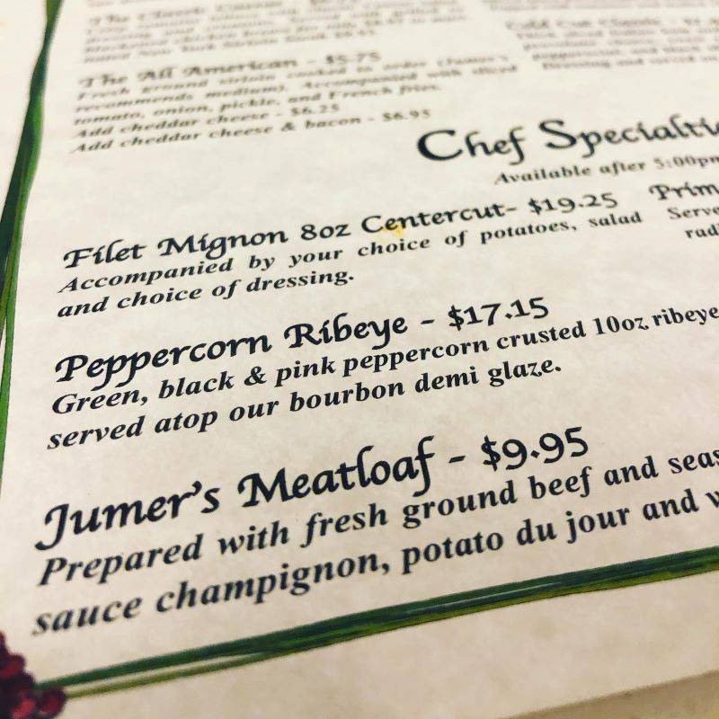 Image: A close up of a menu page that features listings for Filet Mignon, Peppercorn Ribeye, and Jumer's Meatloaf in black script. Photo from Urbanalove Facebook page.