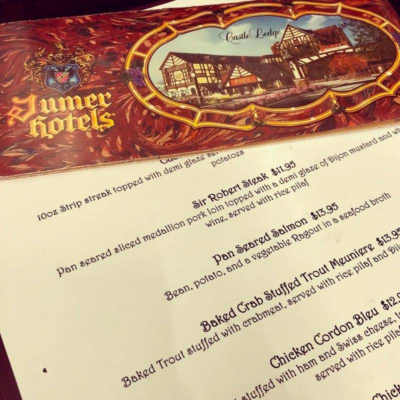 Image: A menu featuring various entrees, prices, and descriptions in black stylized lettering. At the top of the photo is a brochure with an artist's rendering of the hotel and the text Jumer's Hotels. Photo from Urbanalove Facebook page. 