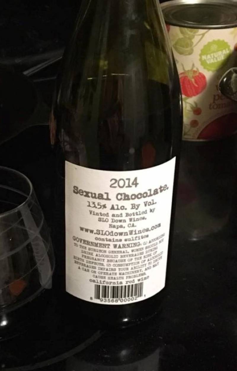 A close up of the label of a bottle of red wine. The label is white and says 2014 Sexual Chocolate at the top. A stemless wine glass sits to the left of the bottle. Photo by Julie McClure.