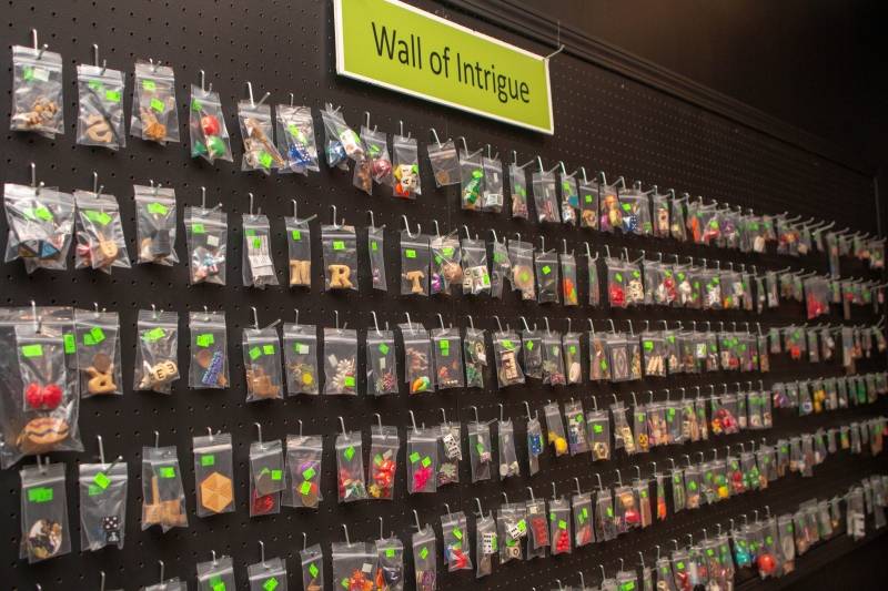 Image: A black pegboard that extend for the length of a wall. There are small plastic resealable bags with various tiny items in them. Photo by Melinda Miller.