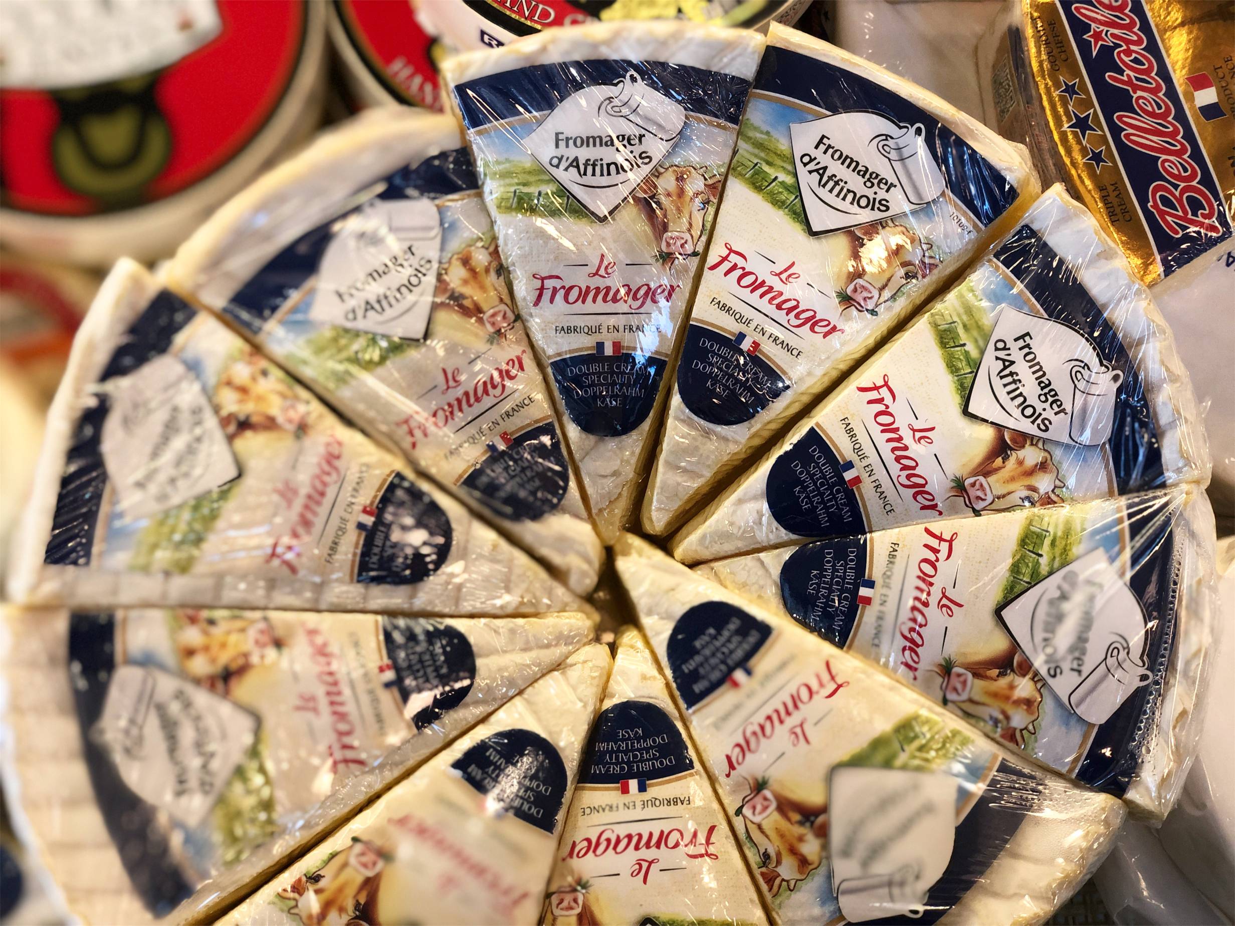 A circle of wedges of Fromager dâ€™Affinois, each individually wrapped. It is a white cheese with a blue stripe label. Photo by Alyssa Buckley.