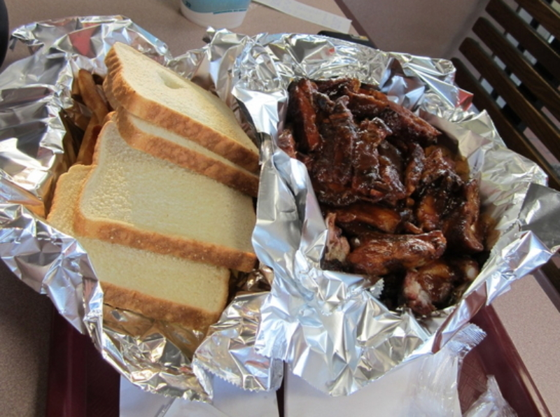 Slices of white bread lay inside tin foil next to a pile of sauced wings on the bone, also in tin foil. Photo by Cody Caudill.