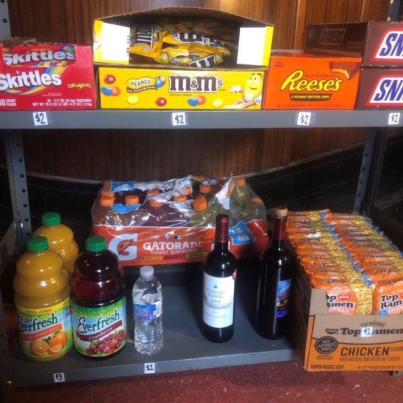 Metal shelves with Skittles, M&M's, Reese's, Snickers, Everfresh Juice bottles, Gatorade bottles, wine bottles, and packages of ramen.