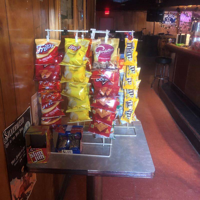 A rack with multiple individual bags of snacks clipped to it: Fritos, Lays, Gardettos, Doritos, M&Ms.