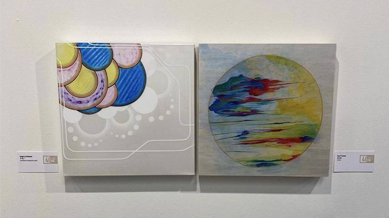 Image: Photo of two paintings from 40 North's Double Take exhibition, Stallmeyer's pale blue, pink, yellow, and white circles on the left and Carol Farnum's multi-colored abstract circle and pale blue background. Photo by Gregory Stallmeyer