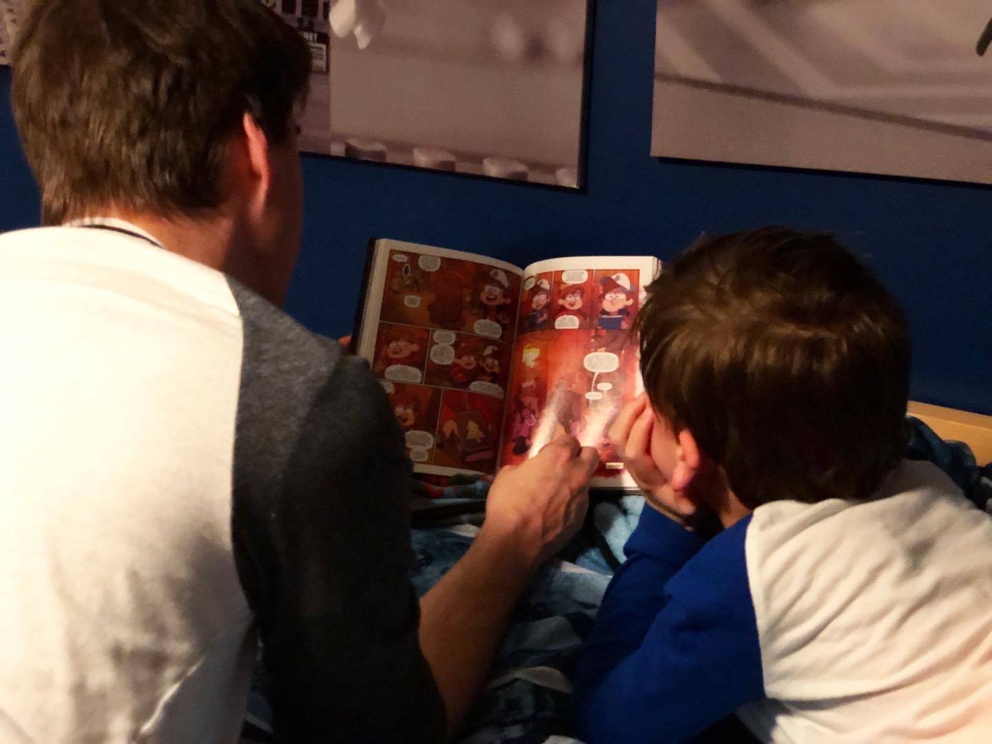 Father reads a story to his son in bed. Photo by Alyssa Buckley.