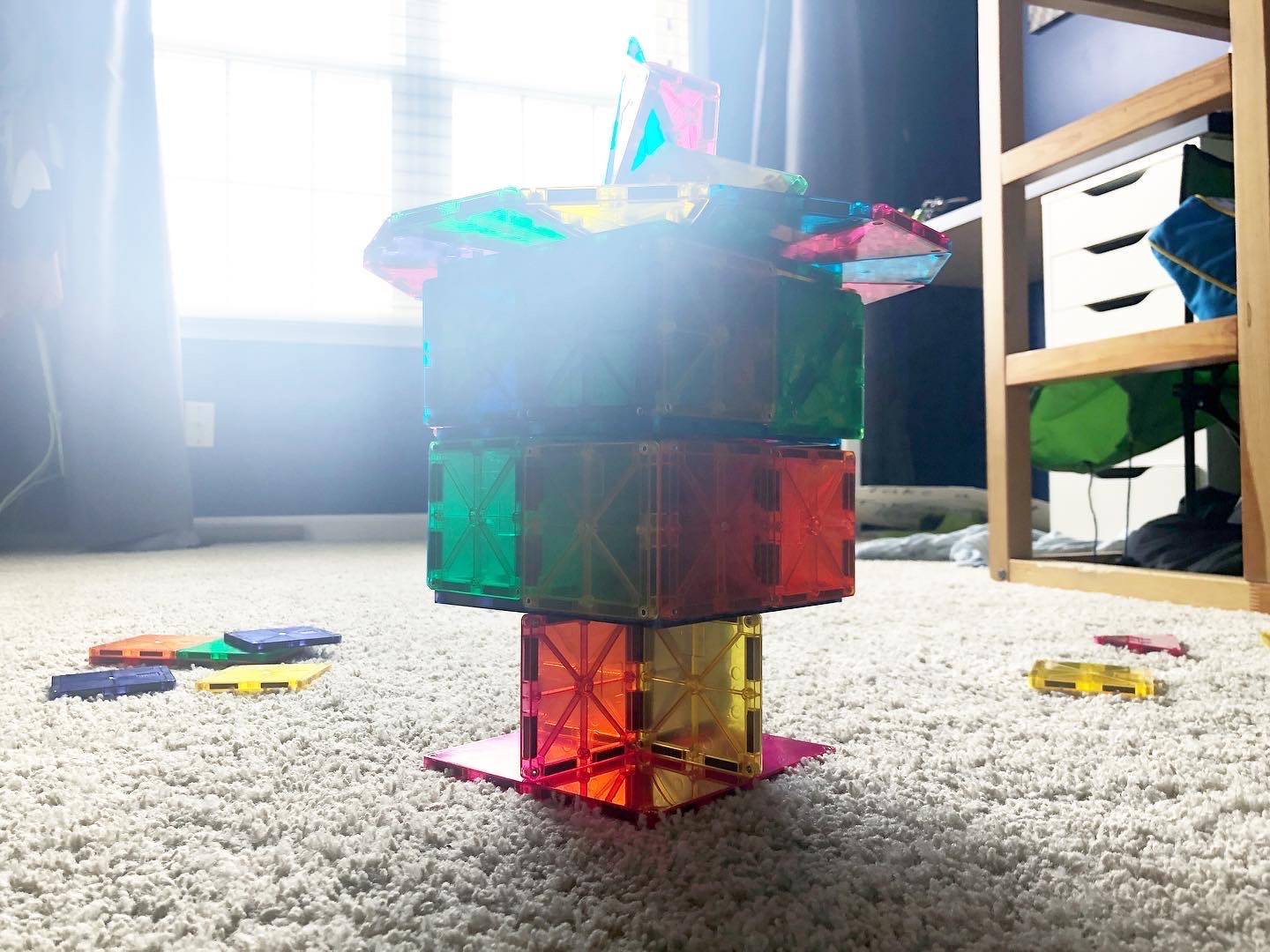 A structure made from the toy Magnatile is on the carpeted floor of a child's bedroom. Photo by Alyssa Buckley.