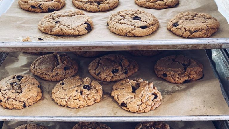 Two metal trays of freshly baked cookies on parchment paper are layered on a baking cart. Photo from Hopscotch Bakery's facebook page.