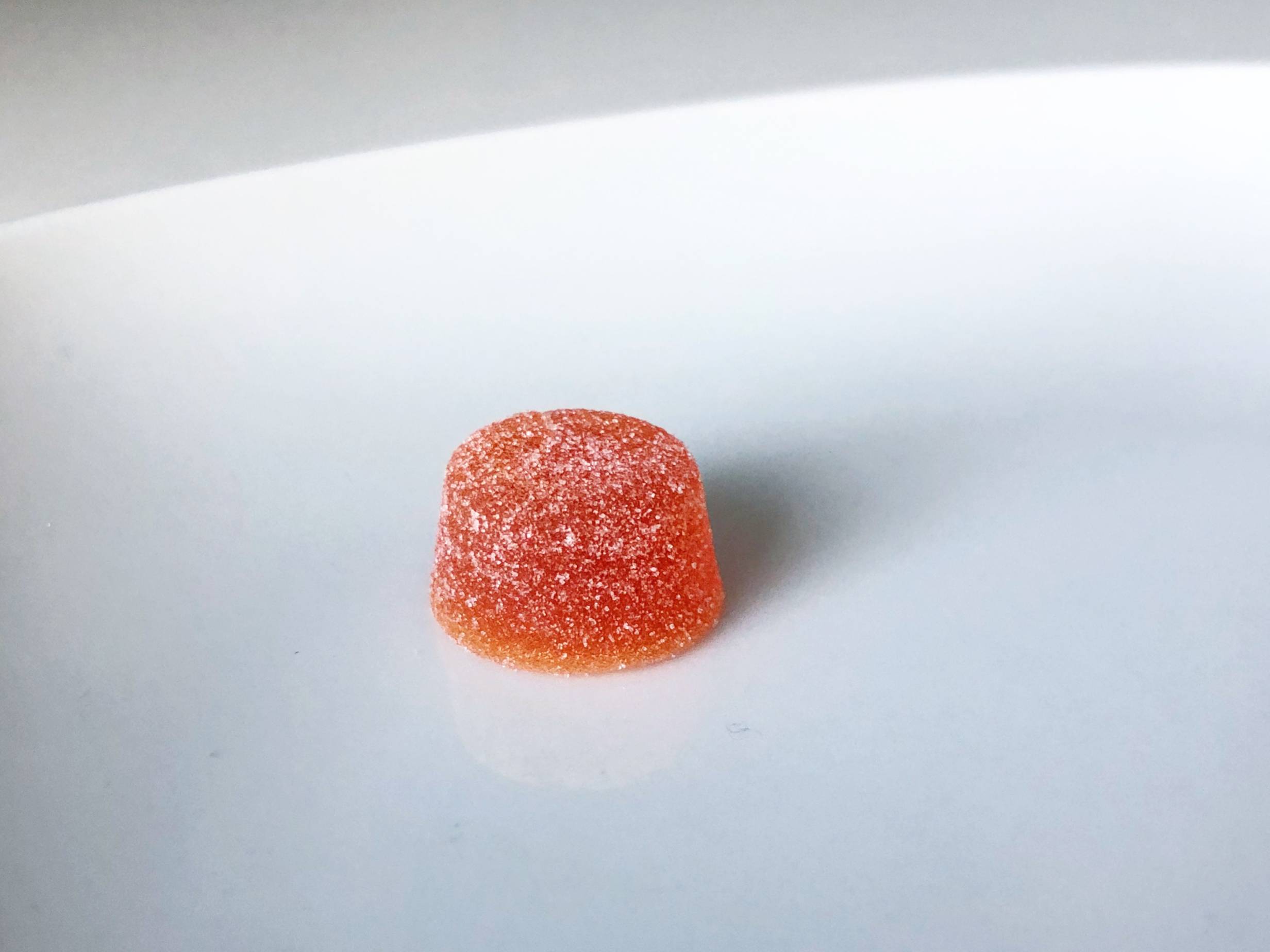 A small cannabis-infused orange gummy covered in sugar sits on a white plate. Photo by Alyssa Buckley.