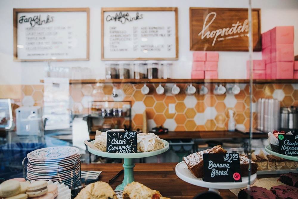 A closer look at the coffee bar: displays of pastries, stacks of dishes, and coffee cups hanging on hooks on the back wall. Photo by Anna Longworth.