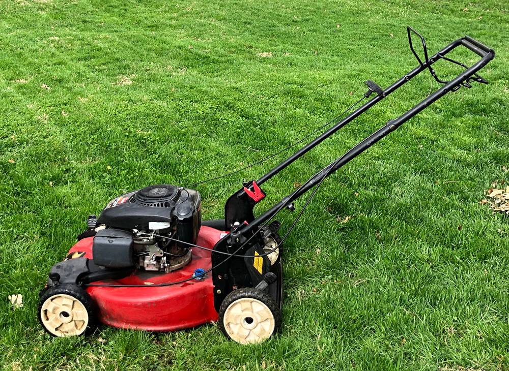 A red push lawn mower is on green, freshly cut grass. Photo by Jessica Hammie. 