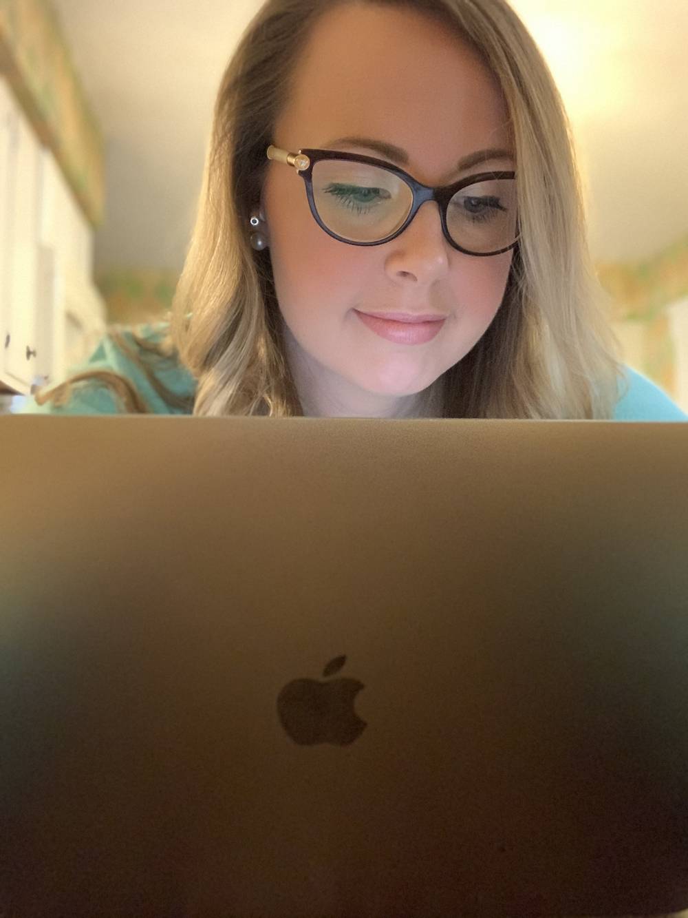 A woman with blonde hair and dark glasses looks down at a laptop computer. Photo by Stephanie Stuart.