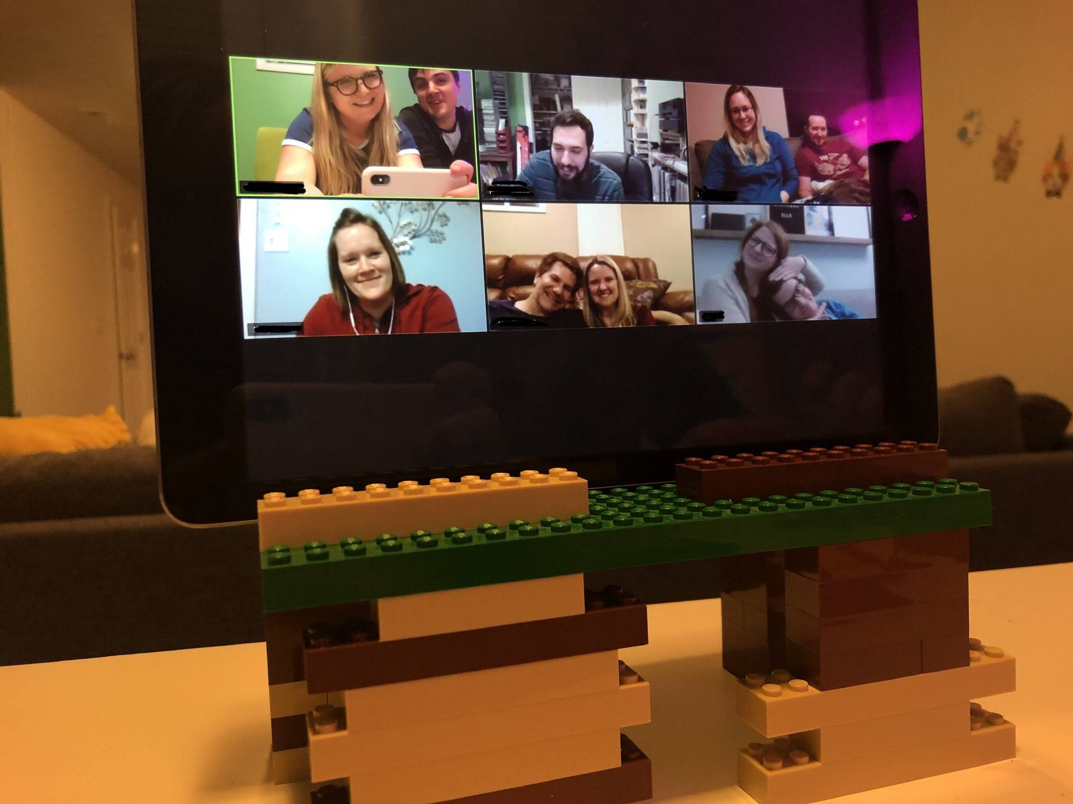 An iPad on a stand made from LEGO bricks shows 6 squares of people. The top left corner pictures the author and her husband. Photo by Alyssa Buckley.