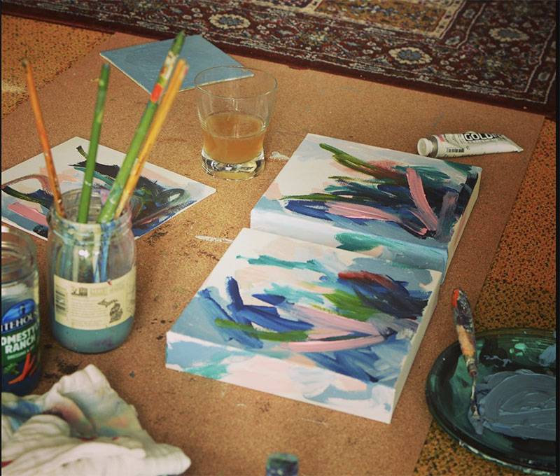 Image: Photo of painting set-up with brushes, canvas, and rags laid out on the floor. Photo from Dana Overman Studio Facebook page.