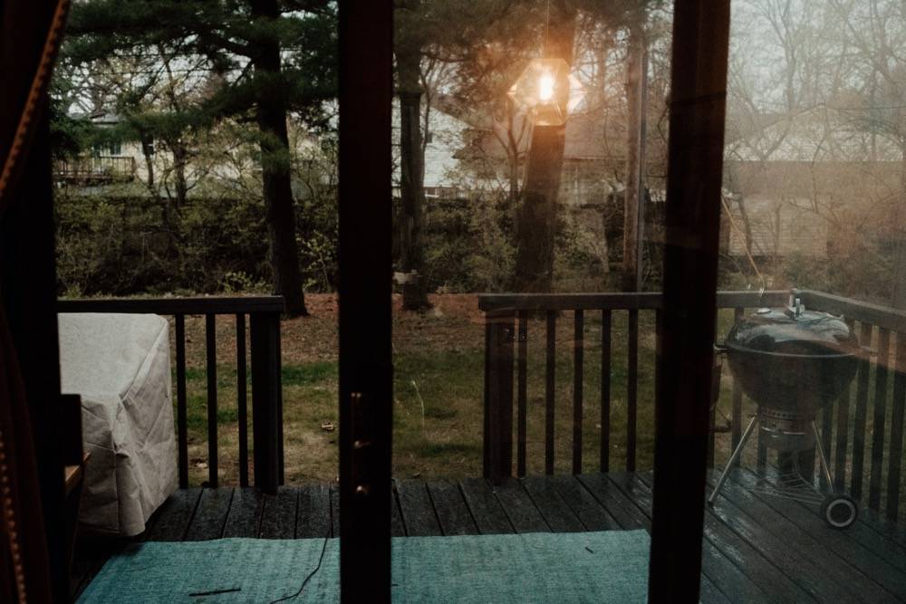 IMAGE: View of a back porch through a sliding glass door. There's a black grill on the right. Photo by Anna Longworth.
