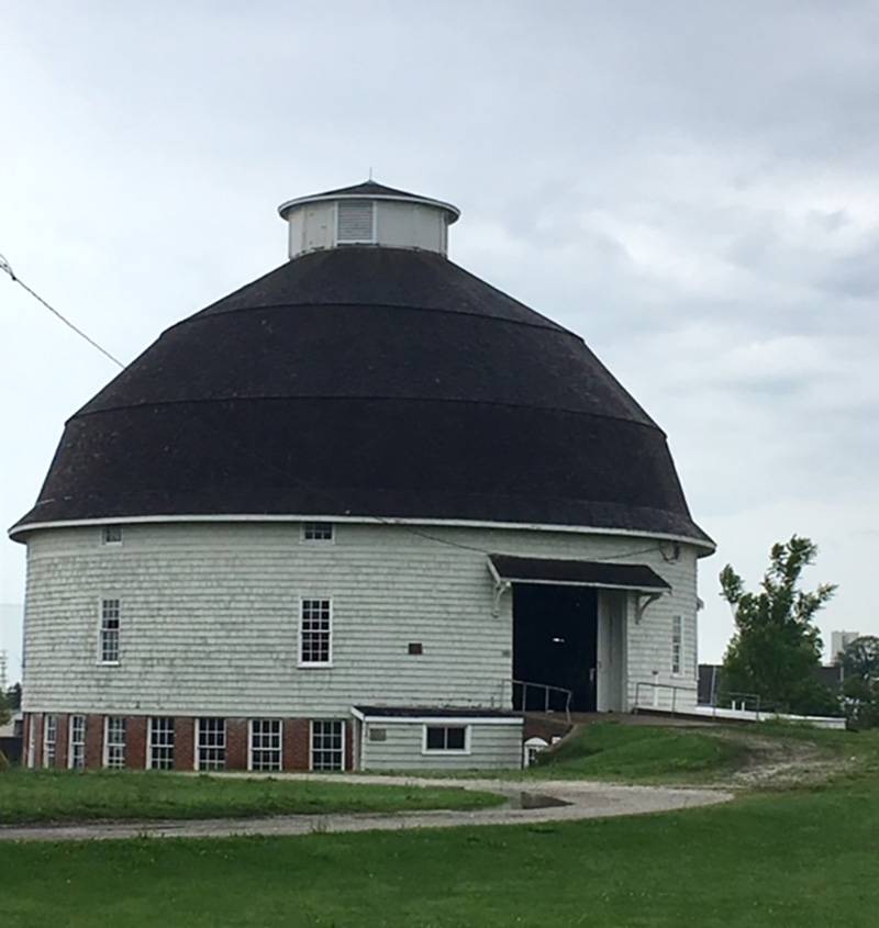 A round white building with a gray domed roof and red brick base. It has several rectangular windows with a grid pattern of window panes. Photo by Rick D. Williams. 