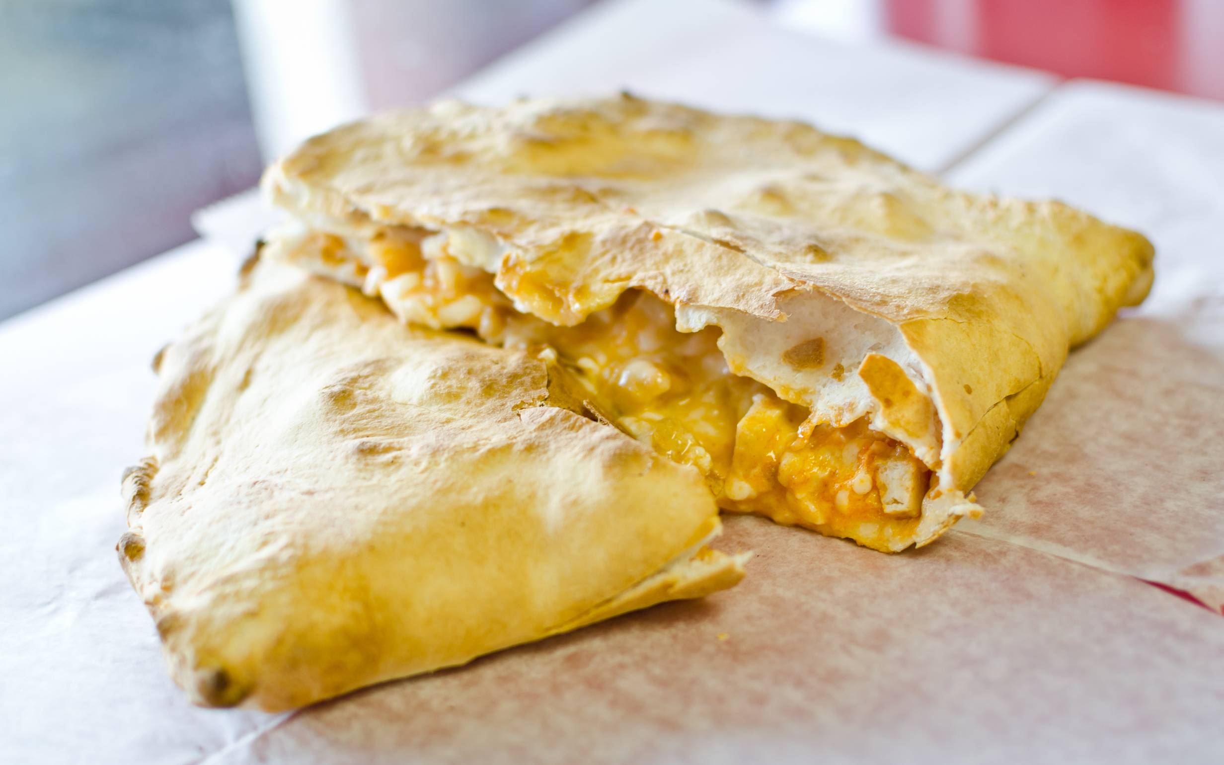 A calzone from D.P. Dough is sliced in half and stacked slightly on top of each other to showcase the warm, melty inside. Photo by D.P. Dough.