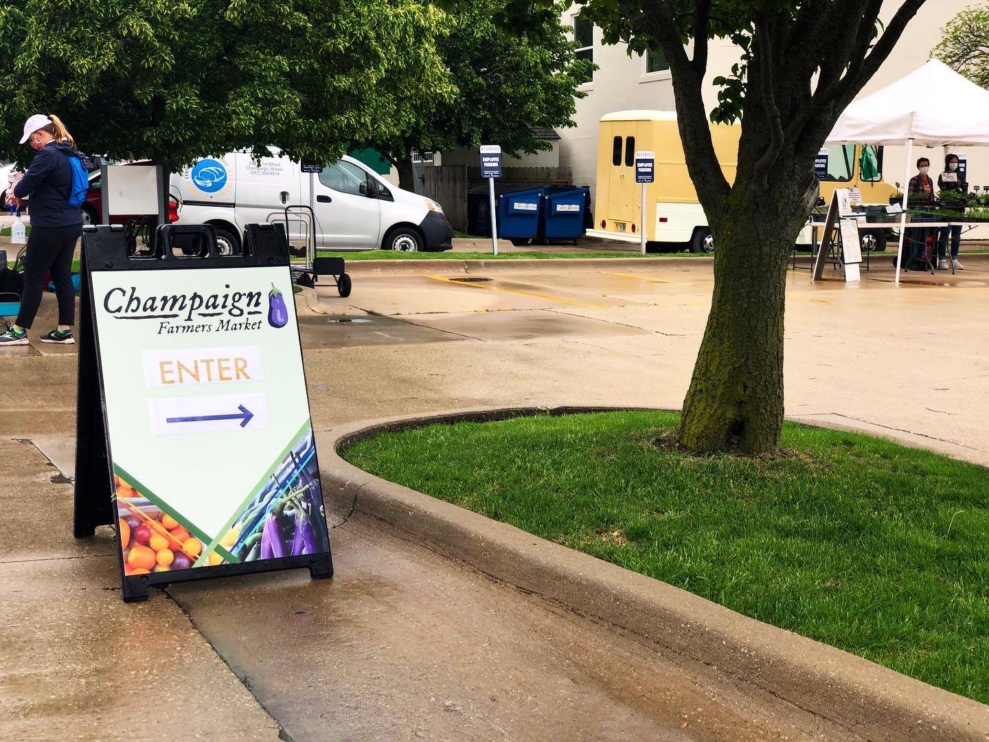 The entrance sign for the Champaign Farmers' Market sits on a parking lot point the direction for social distancing shopping. Photo by Alyssa Buckley.
