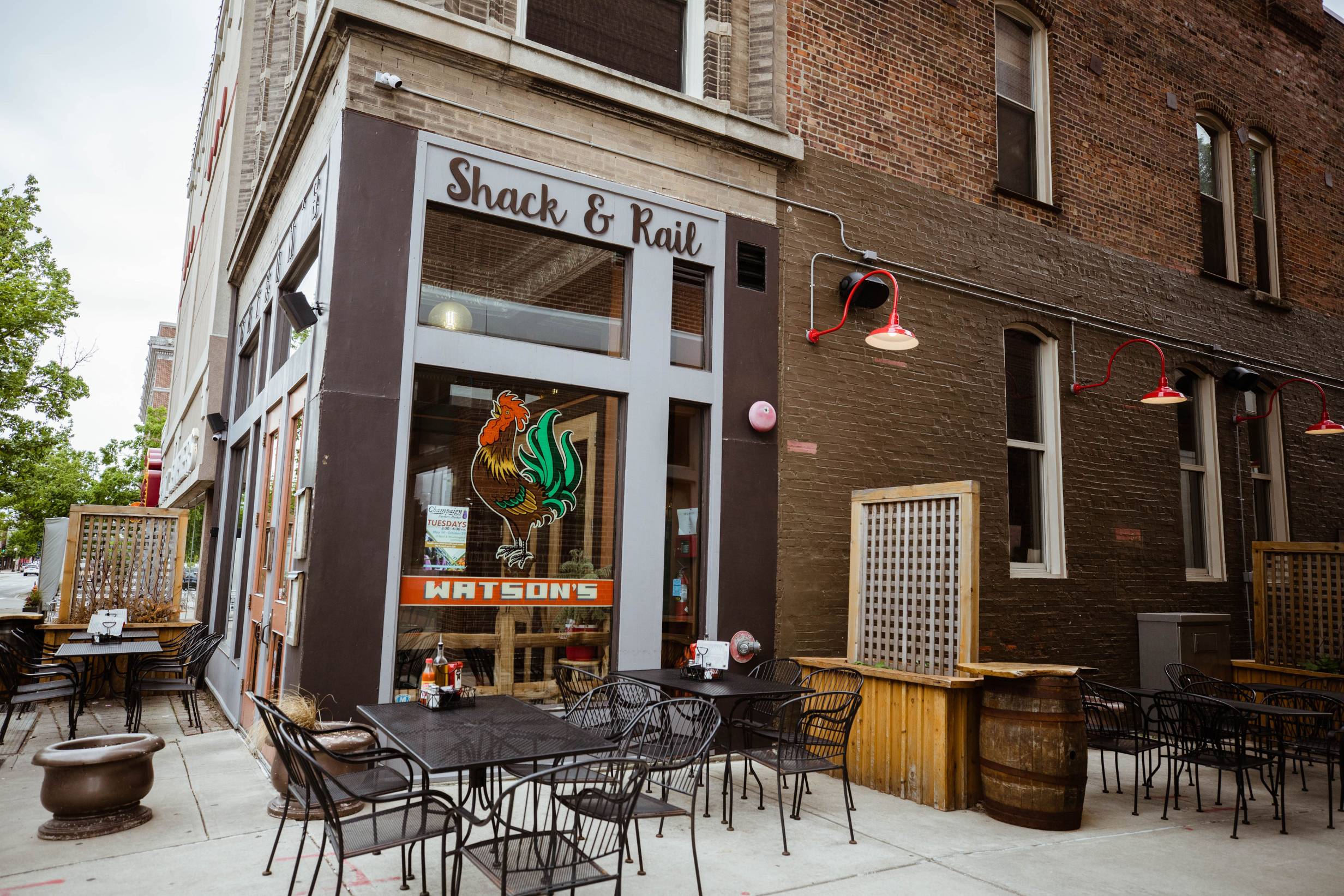 The exterior of Watson's Shack and Rail on Neil Street in downtown Champaign. There are patio chairs sitting empty and a painted chicken is on the window. Photo by Anna Longworth. 