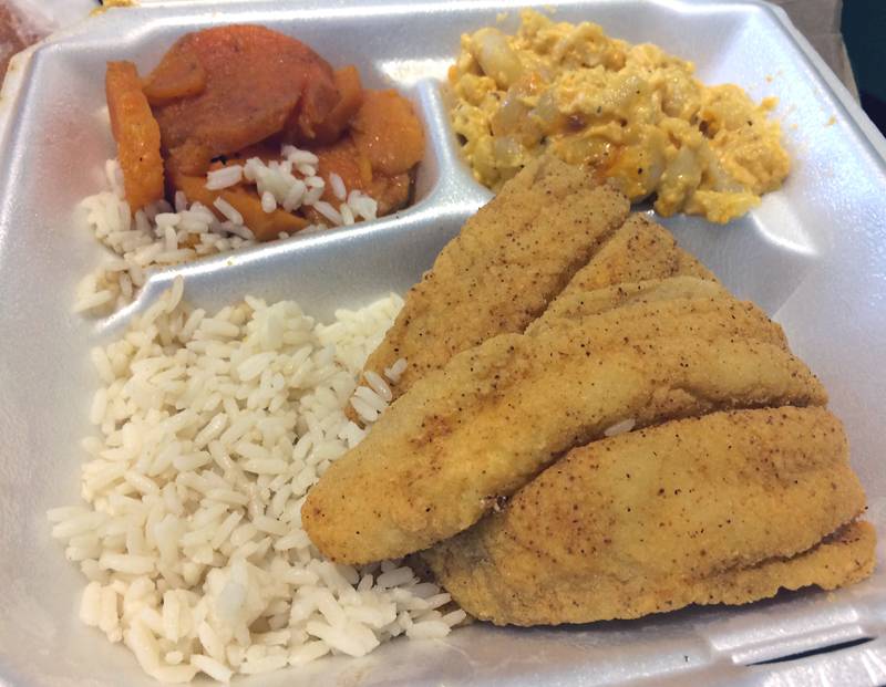Fried fish pieces sit in a styrofoam container over a bed of rice. Two sides are also included. Photo by Jessica Hammie.