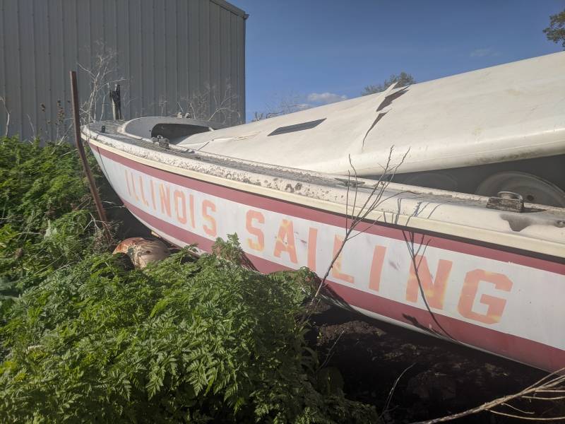 A portion of a rundown white boat and red stripes has the words Illinois Sailing in orange block letters. Photo by Tom Ackerman. 
