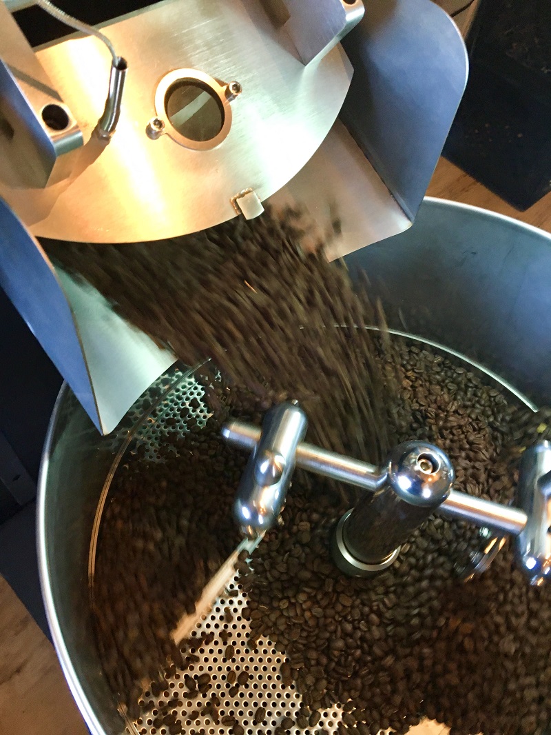 Coffee beans pouring into Page Roasting Company equipment. Photo by Erin Erdman.