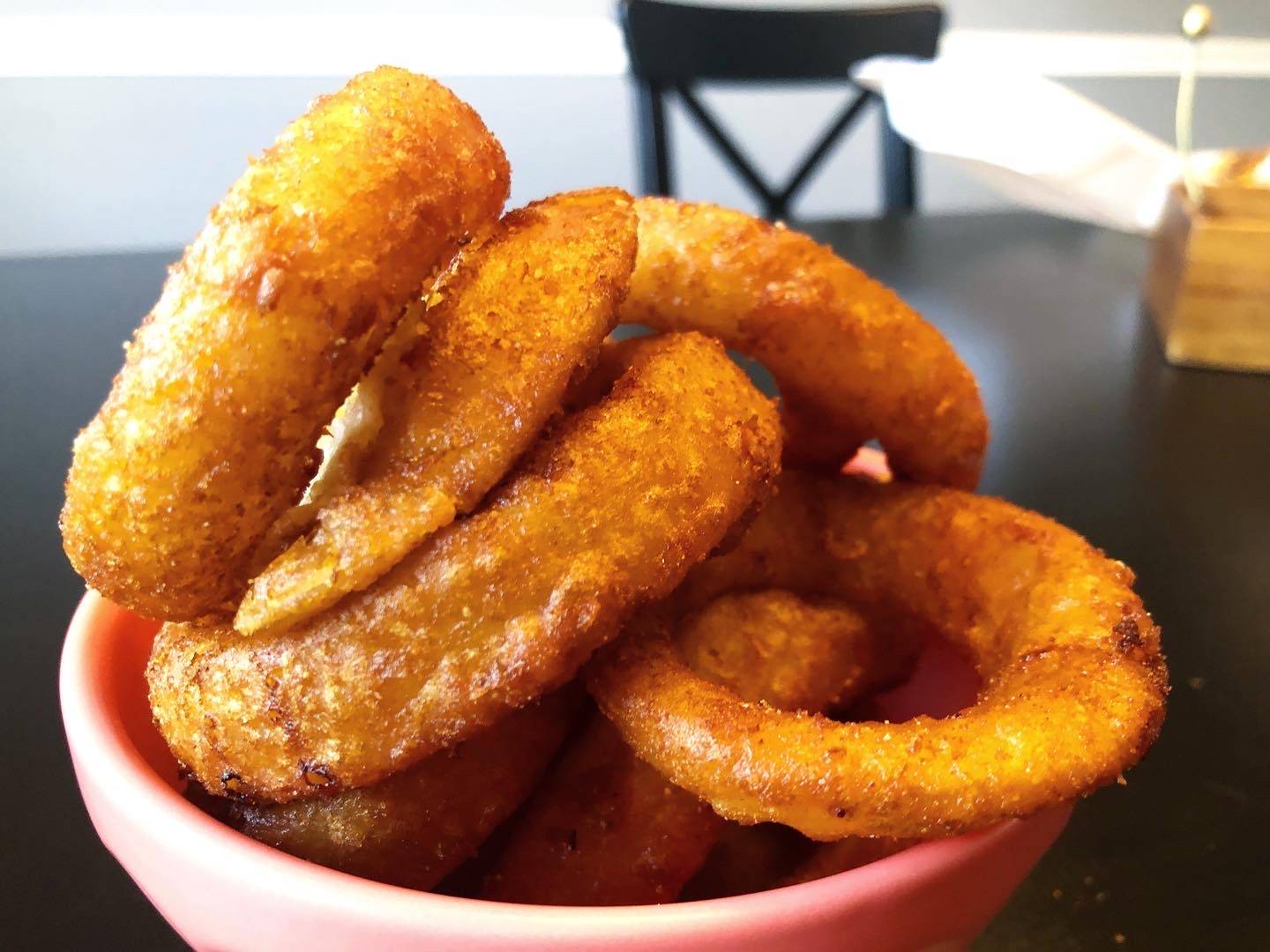 A pink bowl is overflowing with fried onion rings. Photo by Alyssa Buckley.