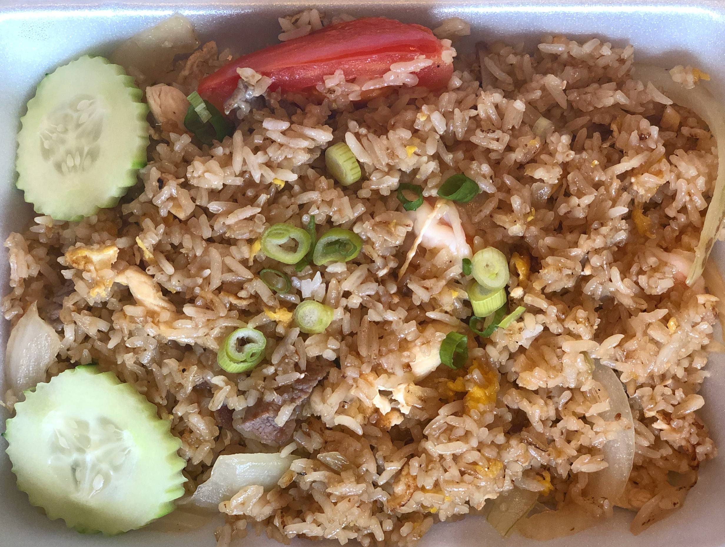Siam Terrace fried rice has brown rice with scallions, beef, chicken, and shrimp. Two beautifully cut cucumber slices lay on the left side. Photo by Alyssa Buckley.