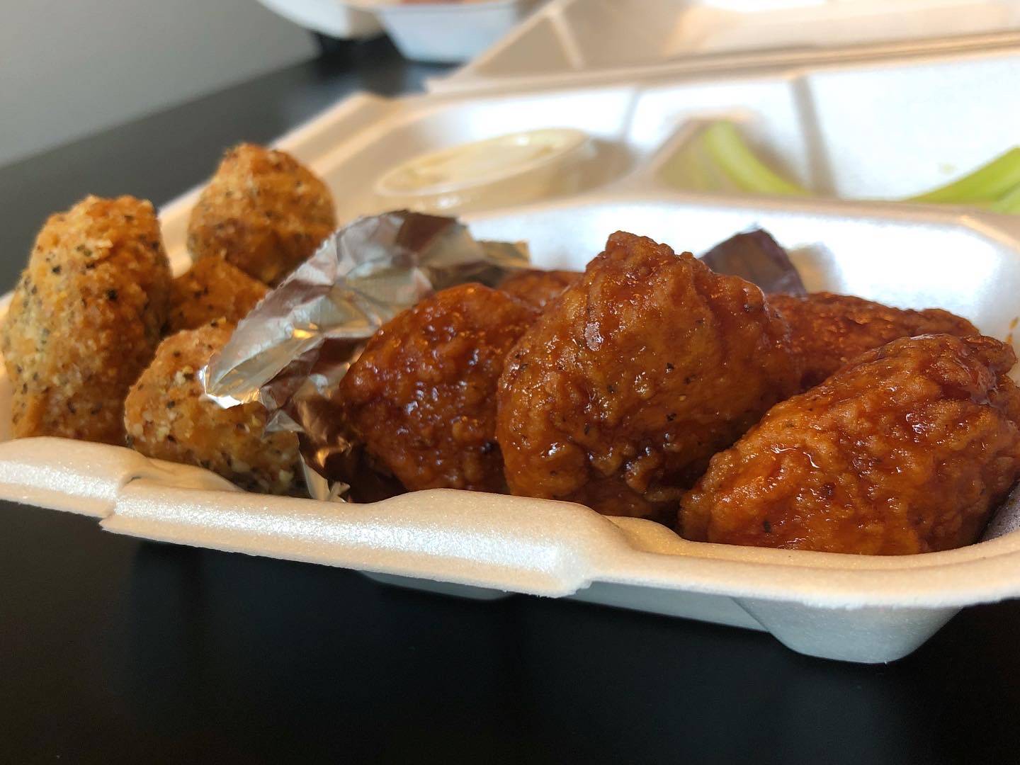 A styrofoam container of boneless wings: one with a dark sauce and one with a dry rub. Photo by Alyssa Buckley.