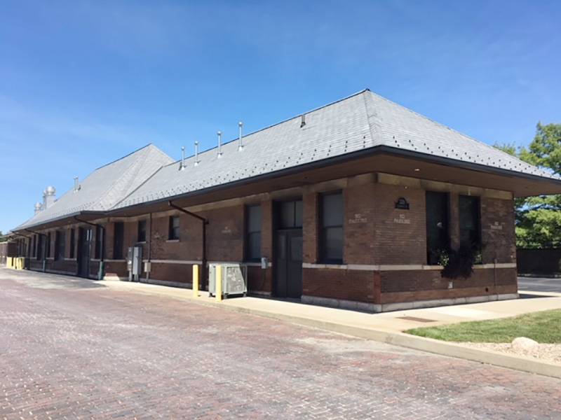 Old Railroad Depot, looking northeast.  Long, slim, brown brick one-story building with gabled roof, light colored shingles. Photo by Rick D. Williams.