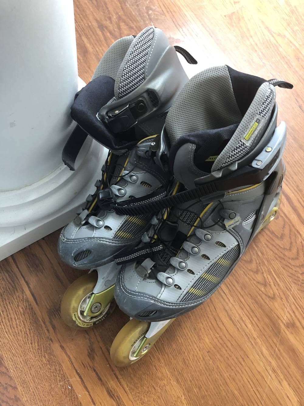 Gray and yellow rollerblades are leaning on a column in a house. The floors are wood floors. Photo by Elizabeth Hess. 