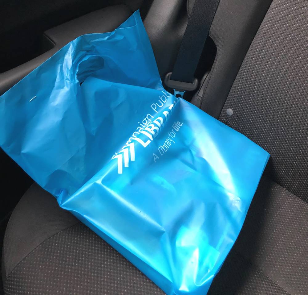 A blue Champaign Public Library bag on the backseat of a car. Photo by Jessica Hammie. 