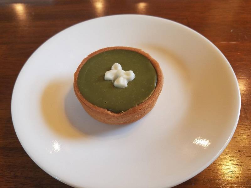 Dark green matcha tart with a small white chocolate ribbon in the center. Photo by Matthew Macomber.