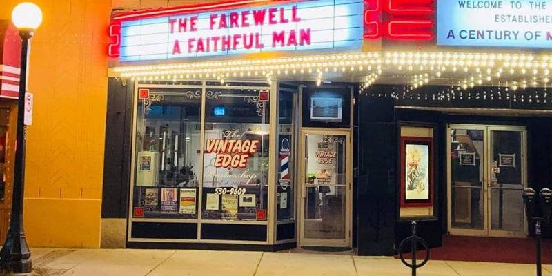 The facade of the barbershop under a lit up marquee that says The Farewell and A Faithful Man. The front of the shop has big rectangular windows and says The Vintage Edge. Photo from Vintage Edge Barbershop Facebook page. 