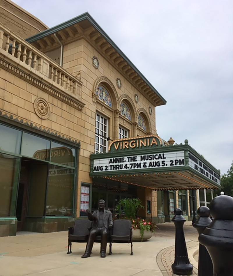Virginia Theater front facade and marquee, looking southwest.  Bronze statue of Roger Ebert sitting on a bench with 