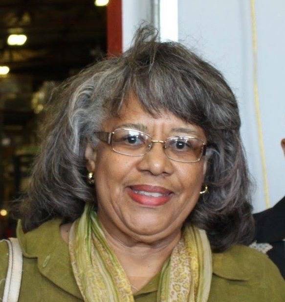 A Black woman with grey and white hair looks at the camera for a photo. She's wearing glasses, and a green shirt/scarf. Photo provided by Patricia McKinney Lewis.â€‹
