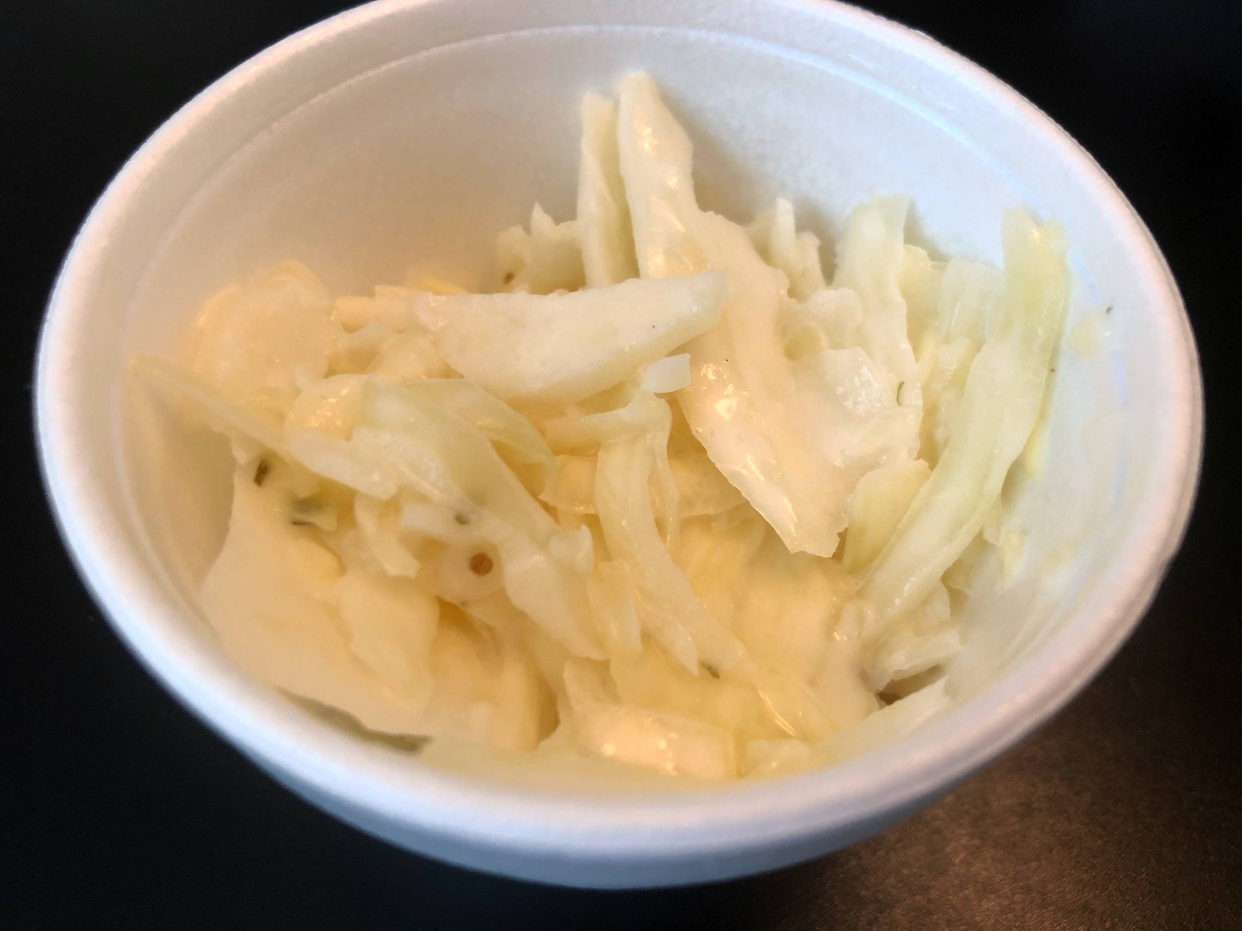 A small portion of white cabbage coleslaw is in a white styrofoam container. Photo by Alyssa Buckley.