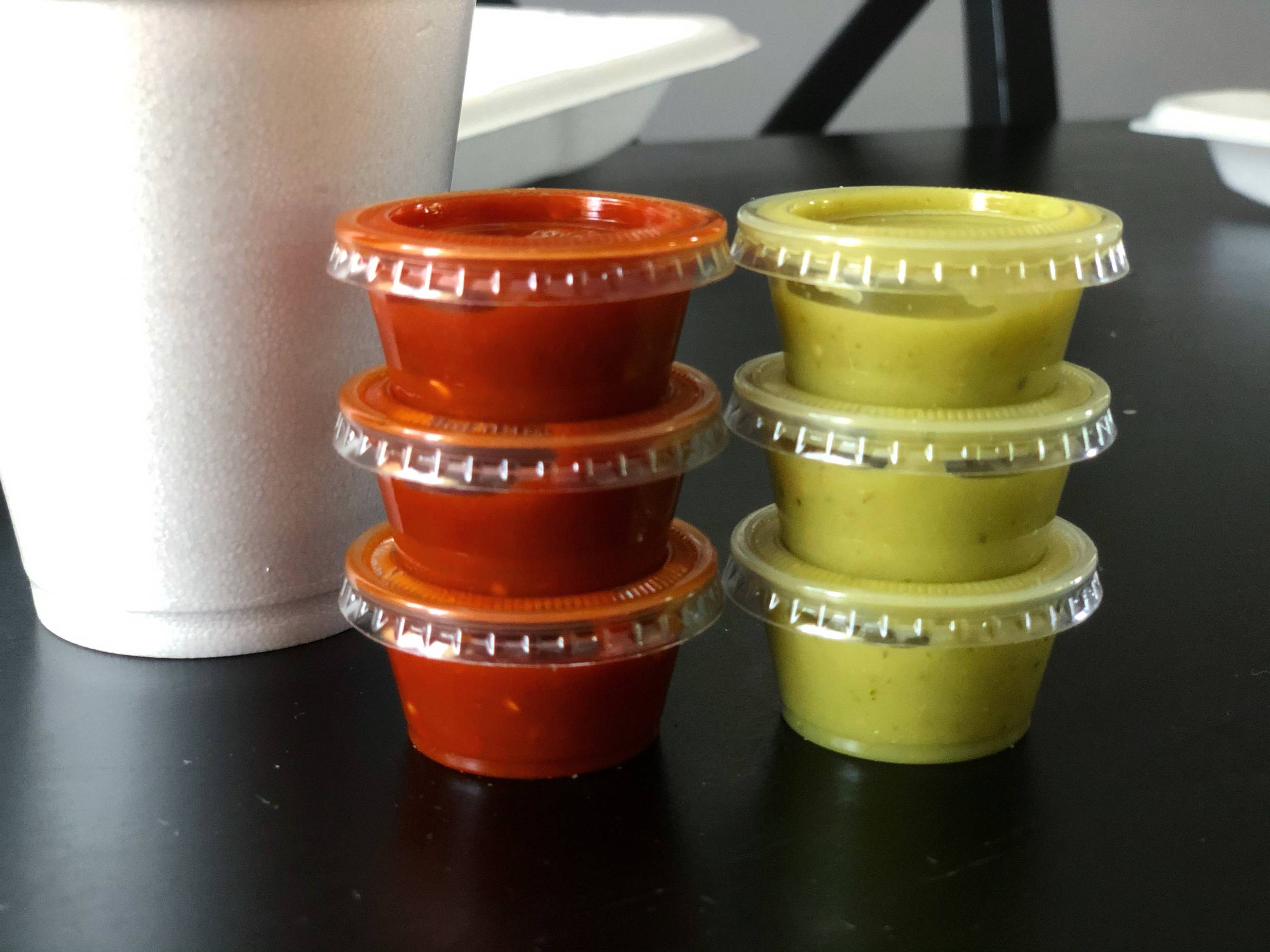 A tower of three small cups of red salsa stands next to a tower of three small cups of green salsa. Photo by Alyssa Buckley.