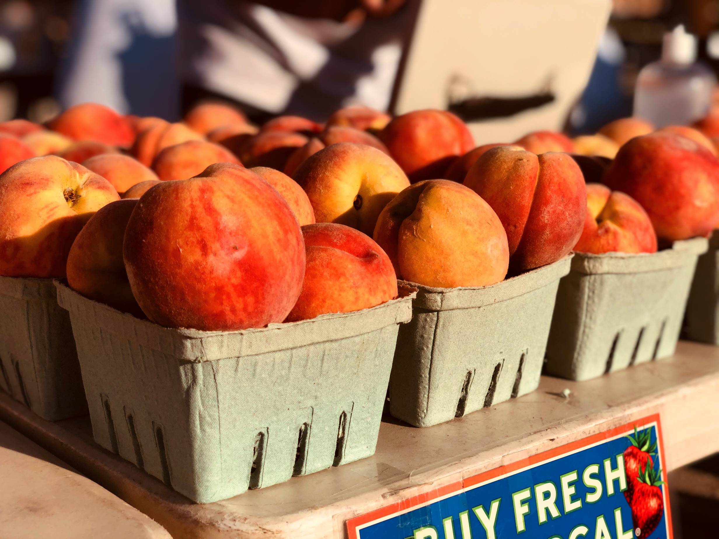Small square baskets filled and overflowing with ripe orange peaches. Photo by Alyssa Buckley.