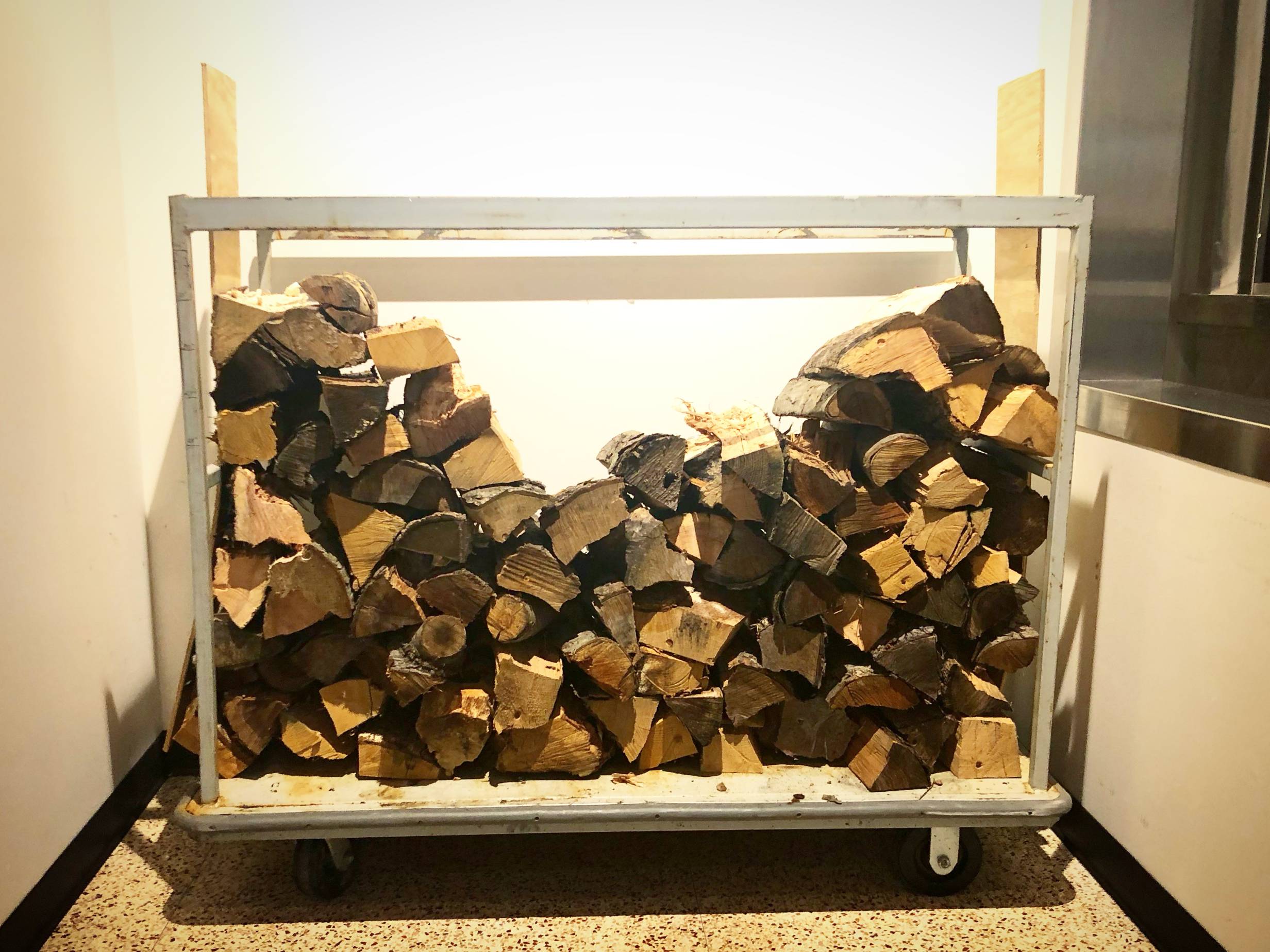 Many cut firewood pieces are stacked on a metal stand. Photo by Alyssa Buckley.