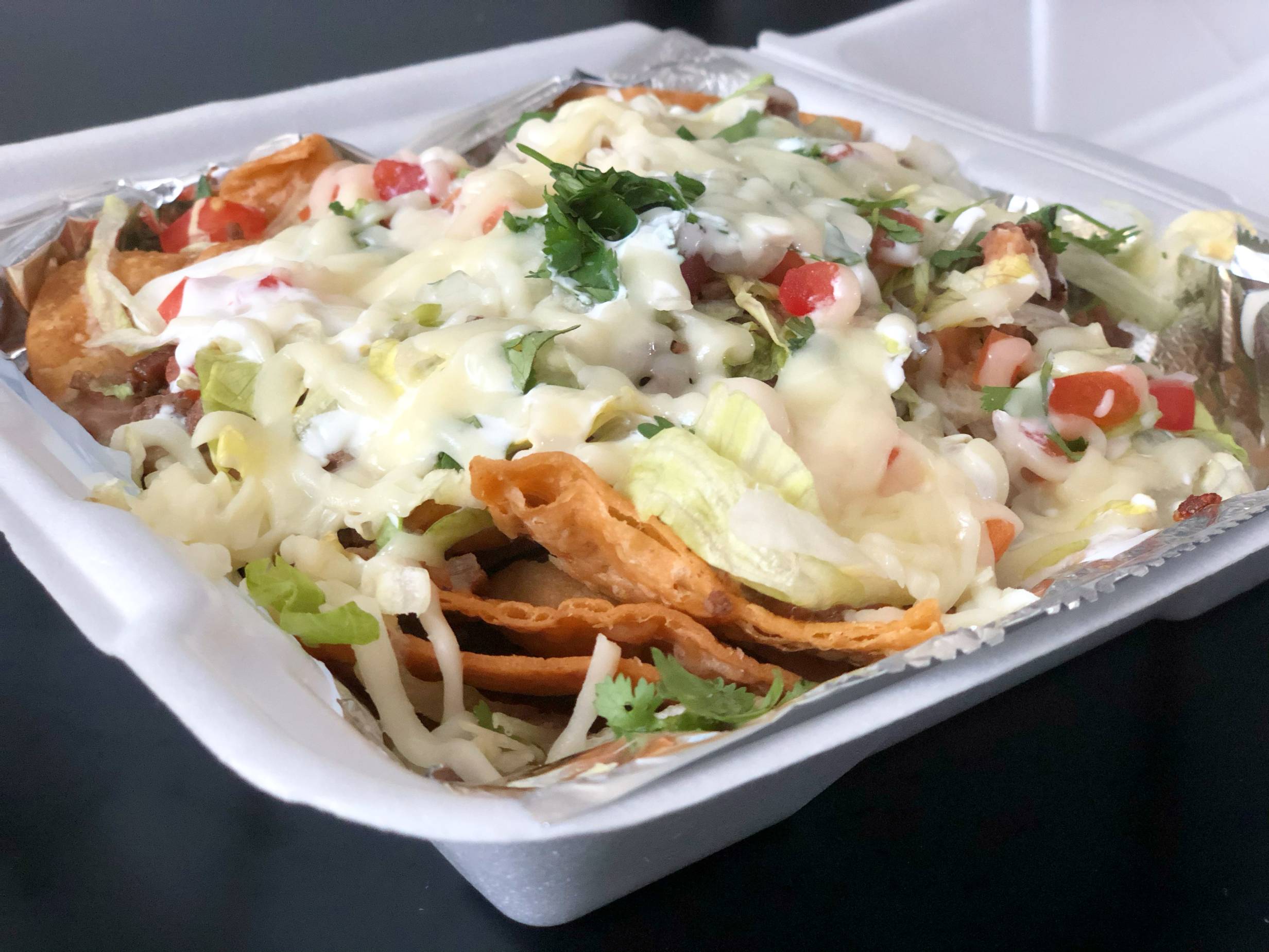 A side shot of nachos featuring crispy corn chips with lots of cheese and sour cream. Photo by Alyssa Buckley.
