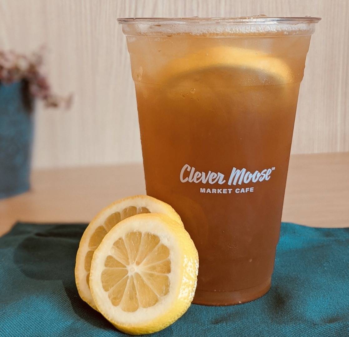 Lodgic's honeybee iced tea is light brown in a plastic cup on a green towel with two lemon slices leaning on the cup. Photo by Betsy Waller.