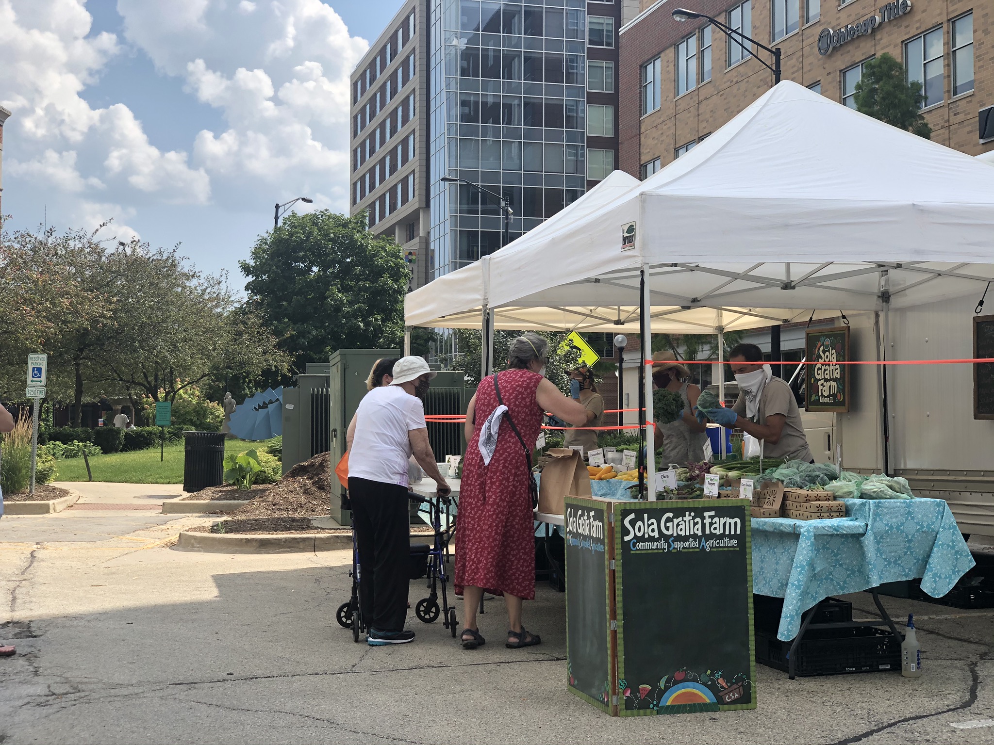 Two shoppers purchase goods from Sola Gratia Farm stand at the Champaign Farmers' Market. Photo by Alyssa Buckley.