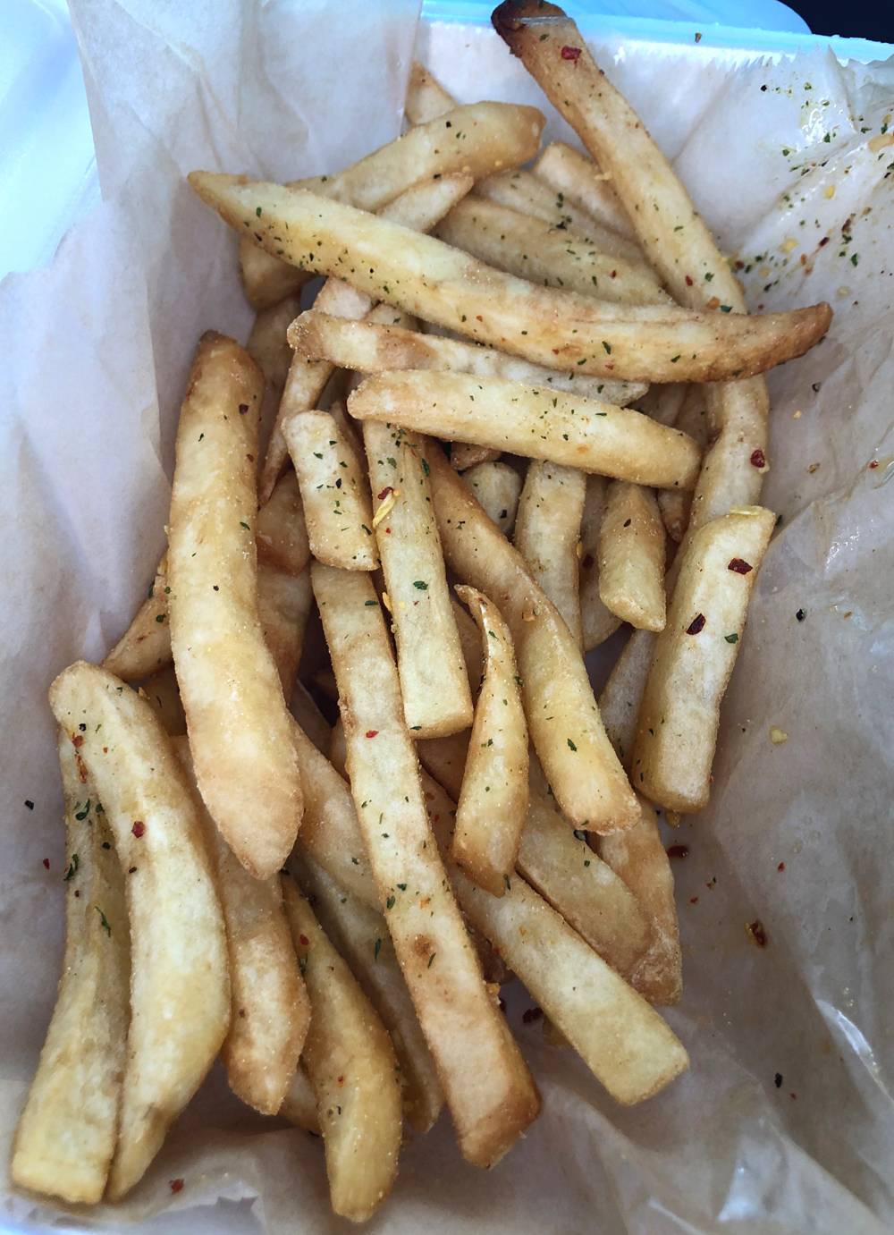 Straight French fries topped wiht a seasoning blend are served in a Styrofoam take out container. Photo by Jessica Hammie. 