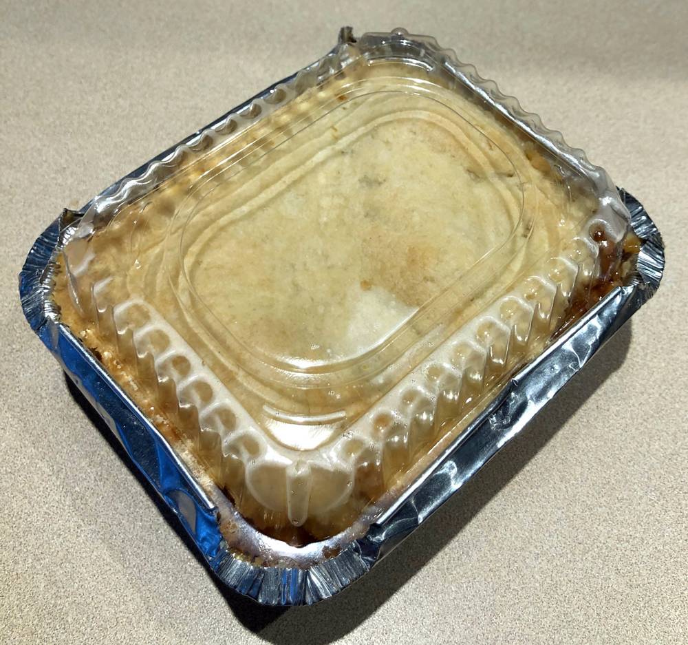 Peach cobbler for two in a disposable tin take out container with a clear plastic lid. Photo by Jessica Hammie. 