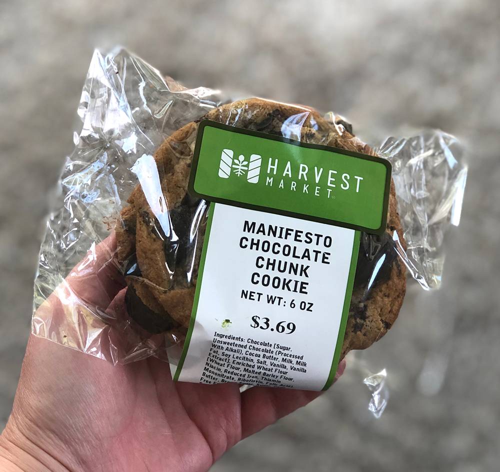 A package of Manifesto Chocolate Chunk cookies from Harvest Market. Two cookies are in a plastic sheath. The package is held in someone's left hand. Photo by Jessica Hammie. 